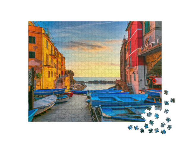 Puzzle 1000 pezzi „Strada del villaggio di Riomaggiore, barche e mare in Cinque Terre al tramonto“