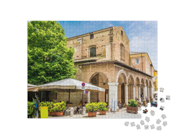 Puzzle 1000 pezzi „Una vista verso il lato di Piazza Roma, nel centro della città di Urbino, in estate.“