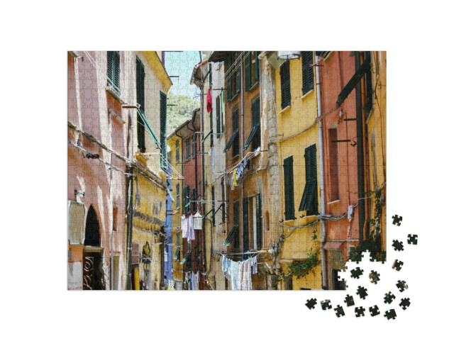 Puzzle 1000 pezzi „Porto Venere in Italia, tipica via del centro storico con case colorate e fili del bucato“