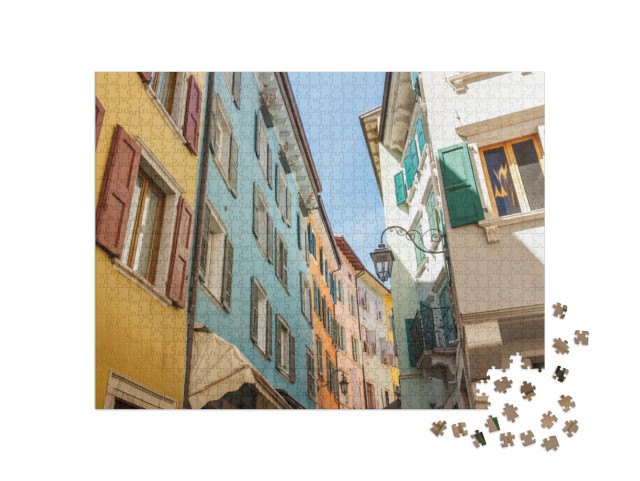 Puzzle 1000 pezzi „Edifici colorati in una strada di Riva del Garda, città sulle rive del Lago di Garda, Italia, Europa.“
