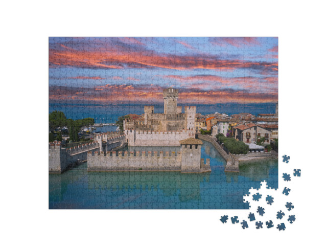 Puzzle 1000 pezzi „Il famoso castello di Sirmione, riflessi del castello nell'acqua sullo sfondo del cielo rosa al tramonto“