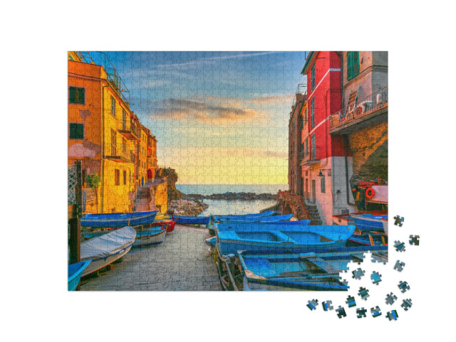 Puzzle 1000 pezzi „Strada del villaggio di Riomaggiore, barche e mare in Cinque Terre al tramonto“
