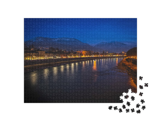 Puzzle 1000 pezzi „Vista notturna della città di Trento, Italia, con le montagne innevate sullo sfondo“