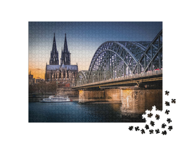 Puzzle 1000 pezzi „Patrimonio mondiale dell'UNESCO: la Cattedrale di Colonia, con il Ponte Hohenzollern in primo piano“