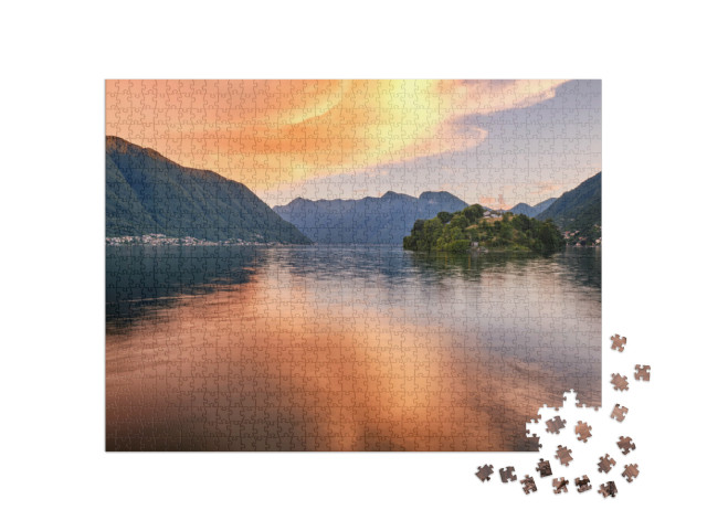 Puzzle 1000 pezzi „Isola Comacina al tramonto, circondata da nuvole arancioni e riflessi colorati dell'acqua, Lago di Como“