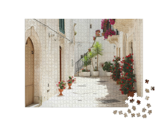 Puzzle 1000 pezzi „Vicolo fiorito nel centro storico di Locorotondo con pareti bianche in Puglia, Italia“