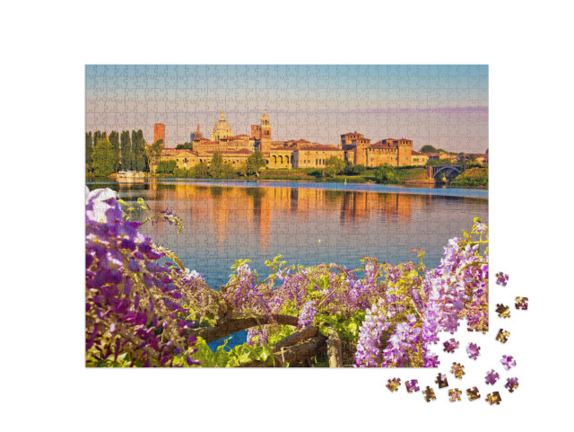 Puzzle 1000 pezzi „Vista mattutina dello skyline di Mantova attraverso i fiori dal Lago Inferiore“