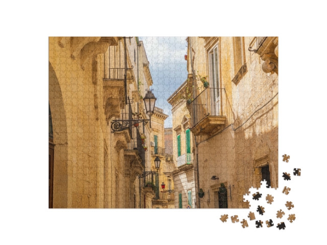 Puzzle 1000 pezzi „Italia, Puglia, Provincia di Lecce, Lecce. Edifici in pietra e balconi in ferro lungo una strada stretta.“