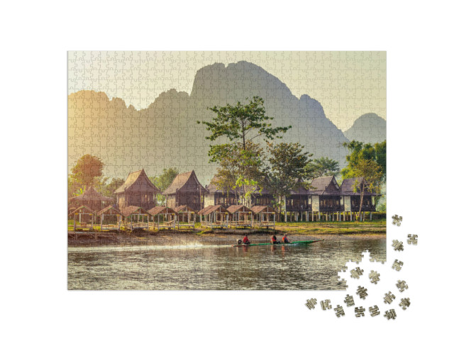 Puzzle 1000 pezzi „Pittoreschi bungalow di villaggio lungo il fiume Nam Song a Vang Vieng, Laos“