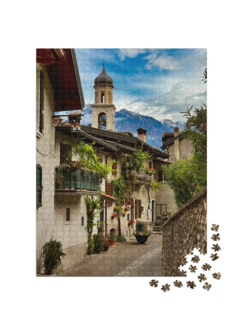 Puzzle 1000 pezzi „Idilliaca strada di un villaggio italiano con piante e fiori verdi. Limone sul Garda“
