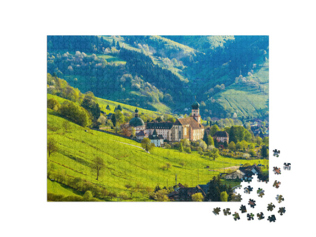 Puzzle 1000 pezzi „Pittoresco villaggio di montagna con case e monastero, Münstertal, Foresta Nera“