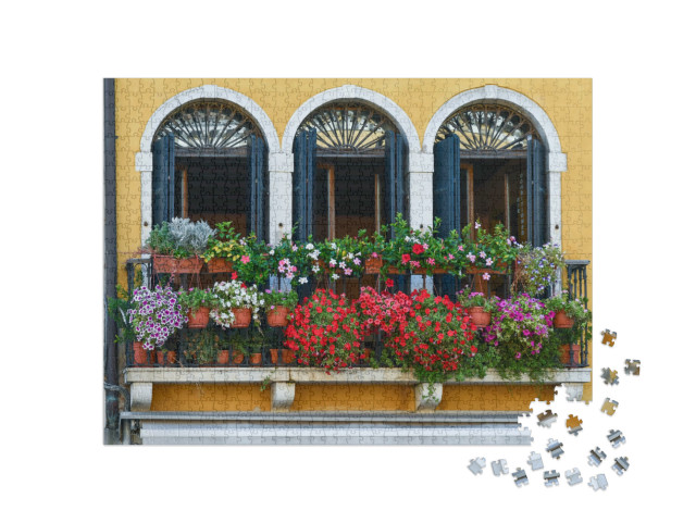 Puzzle 1000 pezzi „Balcone di un antico palazzo con tre porte-finestre ad arco e piante fiorite, Venezia, Italia“