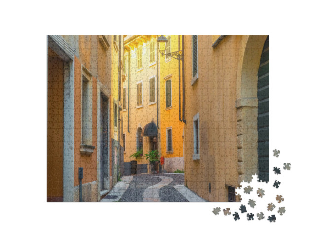 Puzzle 1000 pezzi „Strada medievale stretta e acciottolata con edifici gialli nella città di Verona, Veneto, Italia“
