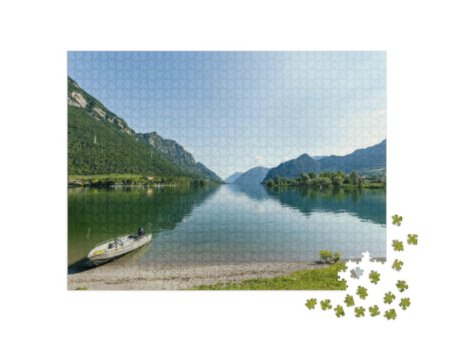 Puzzle 1000 pezzi „Vista del lago d'Idro da Lemprato, un lago prealpino italiano. Il lago è circondato da montagne boscose“