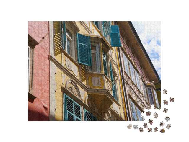 Puzzle 1000 pezzi „Centro storico di Bolzano con ornamenti sulla facciata in una soleggiata giornata estiva“