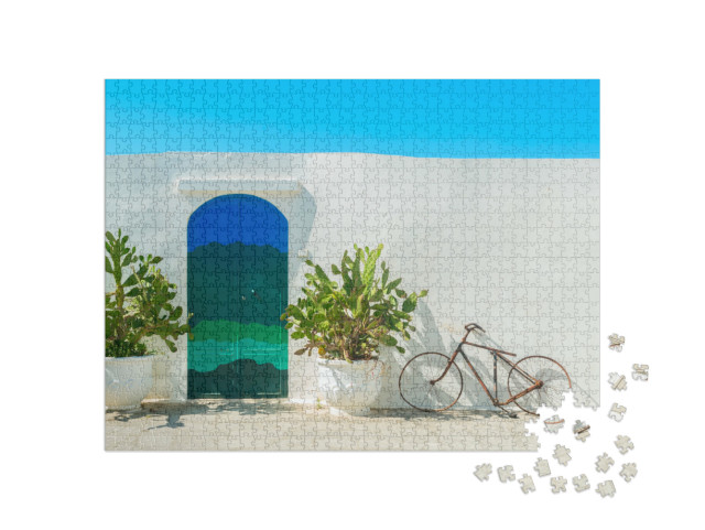 Puzzle 1000 pezzi „La porta blu con cactus e le tradizionali mura bianche della città di Ostuni (Puglia - Italia).“